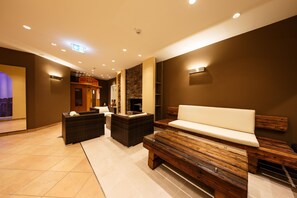 A spa area with a reception desk, seating, and a stone wall. - Hotel Bayerischer Hof Miesbach, BW Premier Collection (Miesbach)