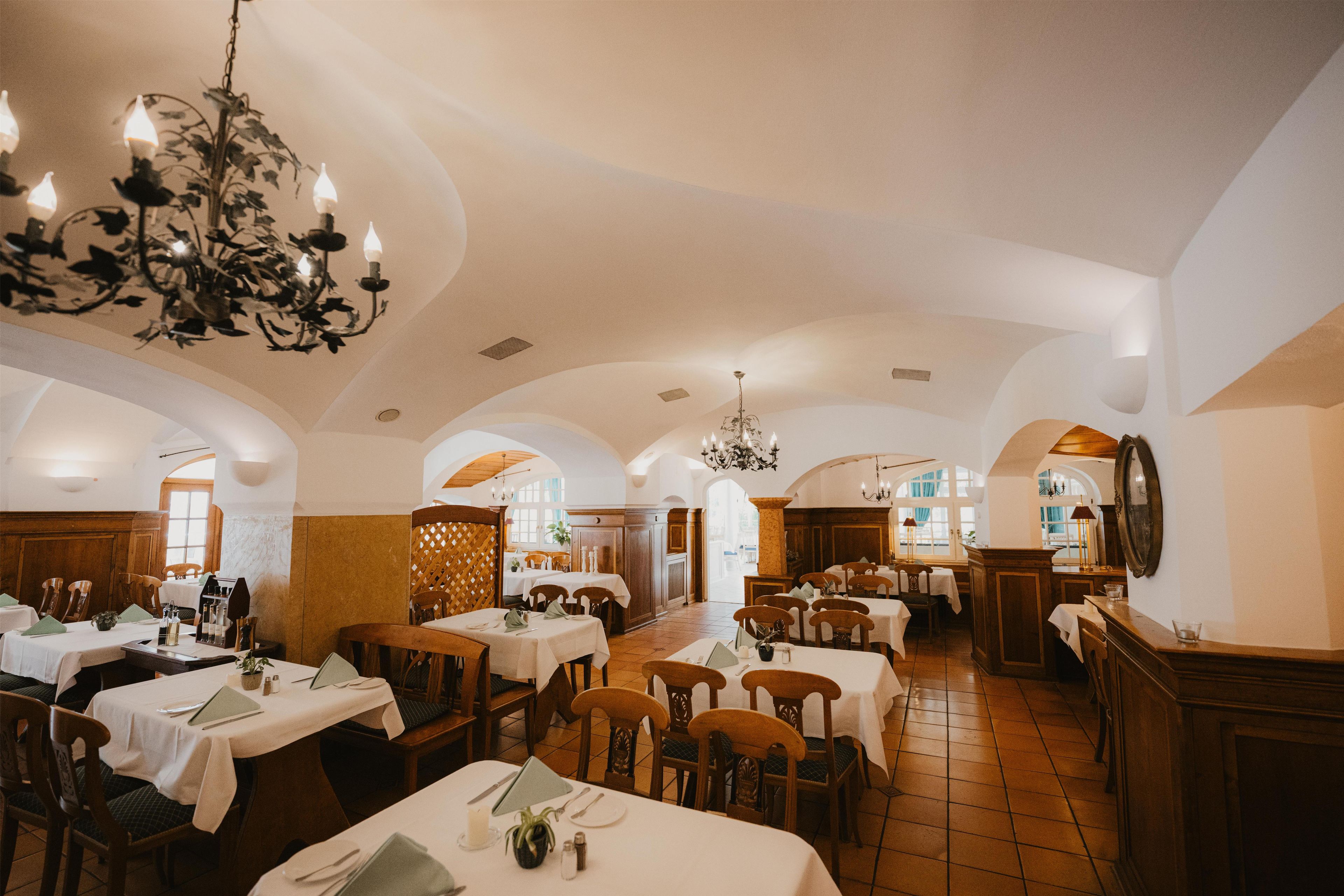 Ein Restaurant mit mehreren Tischen, Stühlen und Kristallleuchtern.