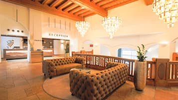 A reception area with a check-in desk, a reception sign, and a seating area with a large cushioned sofa.