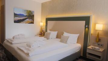 Ein Hotelzimmer mit zwei Betten, einem Landschaftsbild und einem Nachttisch mit einer Lampe.
