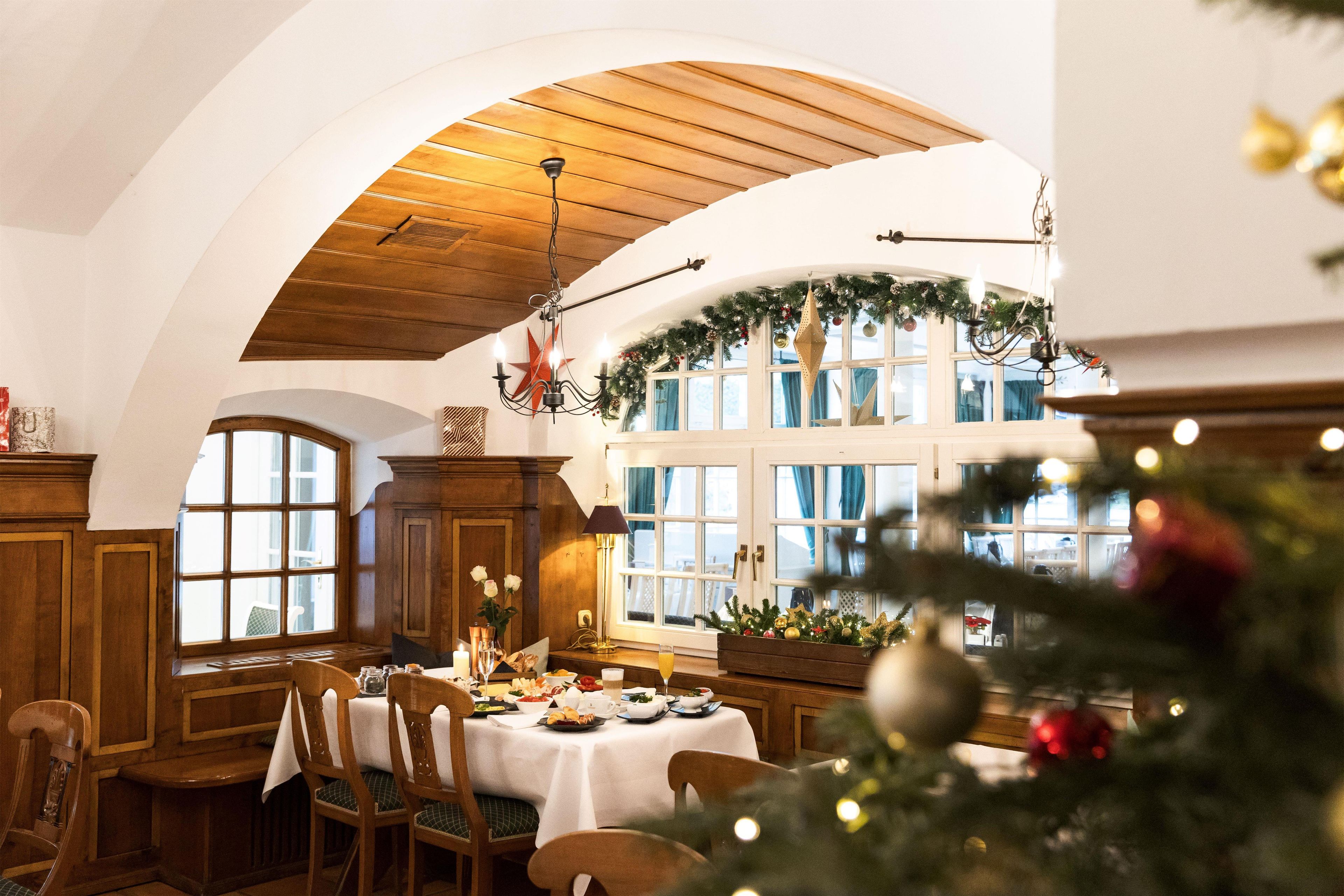 Ein Essbereich mit hoher, gewölbter Decke, Holzmöbeln und einem Weihnachtsbaum im Vordergrund.