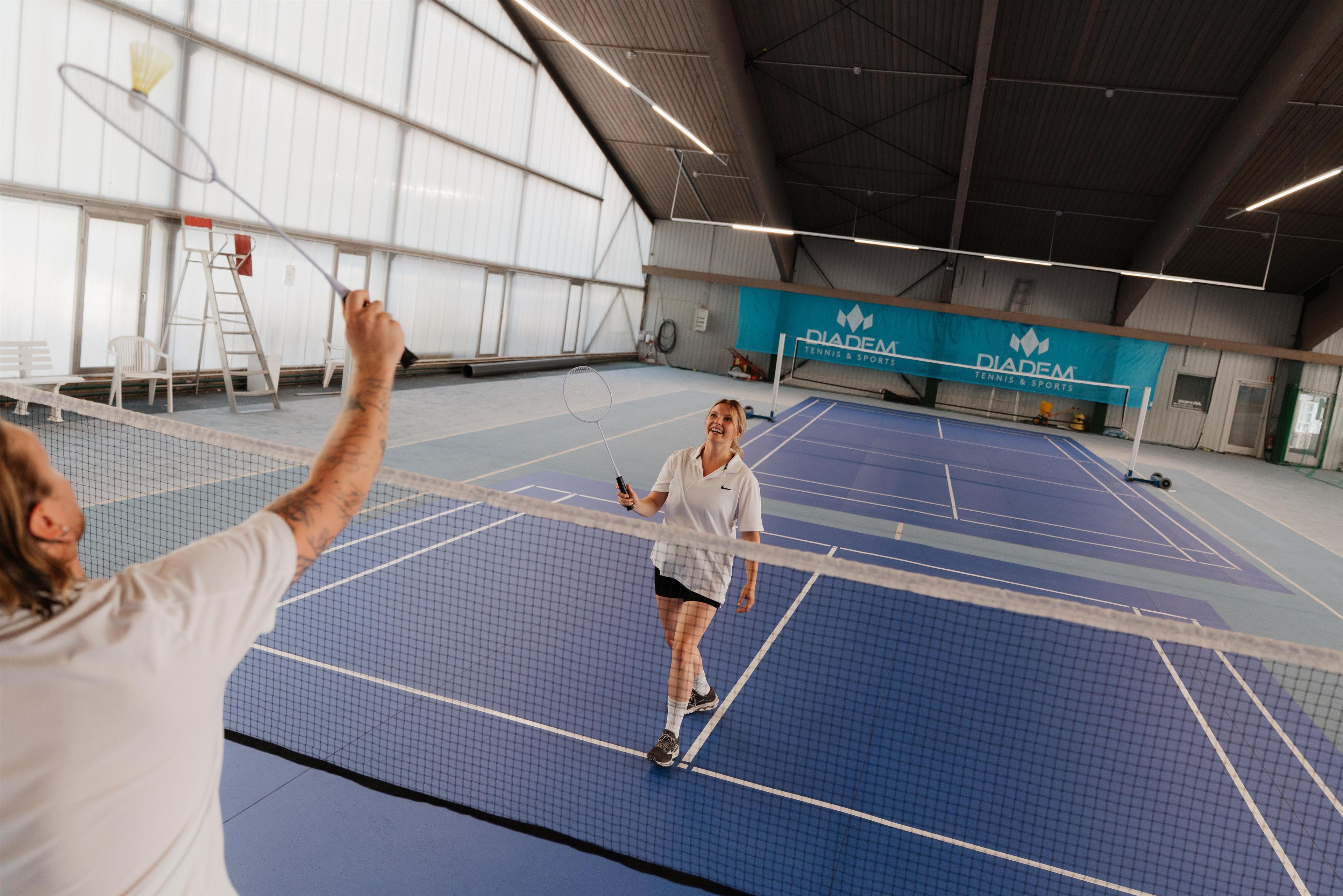 Un court de tennis intérieur équipé d’un filet, d’une raquette de tennis et d’une balle de tennis.