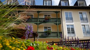 A multi-story building with balconies, flower boxes, and a wooden fence. - Hotel Bayerischer Hof Miesbach, BW Premier Collection (Miesbach)