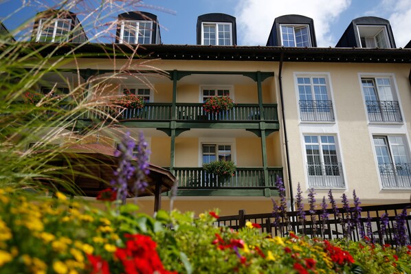 A multi-story building with balconies, flower boxes, and a wooden fence. - Hotel Bayerischer Hof Miesbach, BW Premier Collection (Miesbach)