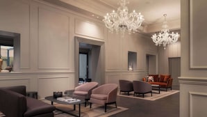 En rummelig lobby med et moderne design, der inkluderer en stor lysekrone, behagelige siddepladser og en neutral farvepalet.