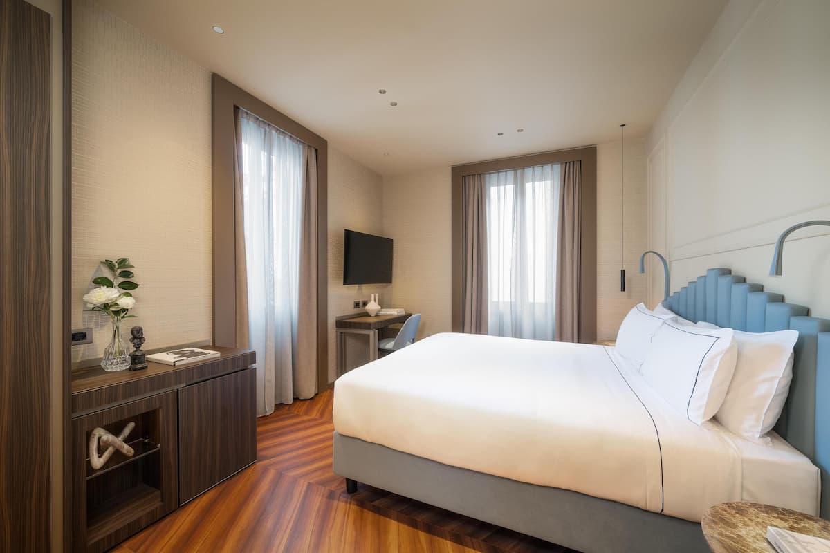 Et moderne hotelværelse med en stor seng, et skrivebord, et fjernsyn og en trappe.