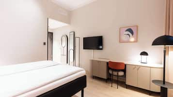 A hotel room with a bed, a desk, a chair, a TV, and a lamp.