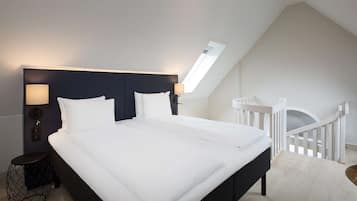 Un dormitorio moderno con una cama grande, una mesita de noche, una lámpara y vistas al exterior a través de un tragaluz.
