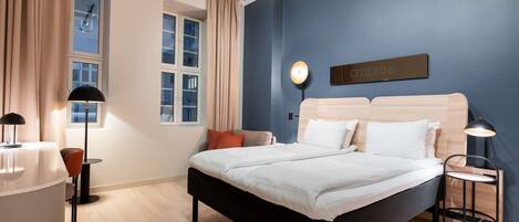 Un dormitorio moderno con cama, mesitas de noche, lámpara y ventana con cortinas.