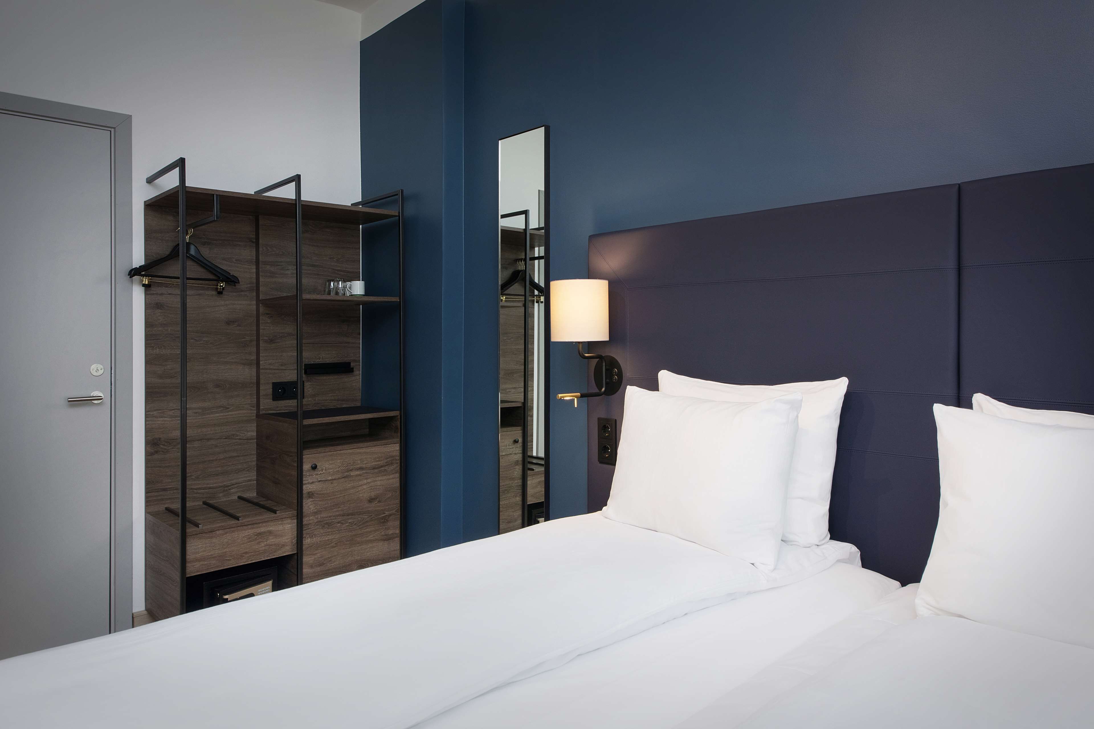 Una habitación de hotel moderna con cama, armario y espejo.