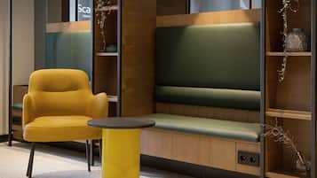 A modern seating area with a yellow chair, a green cushioned bench, and a small round table.