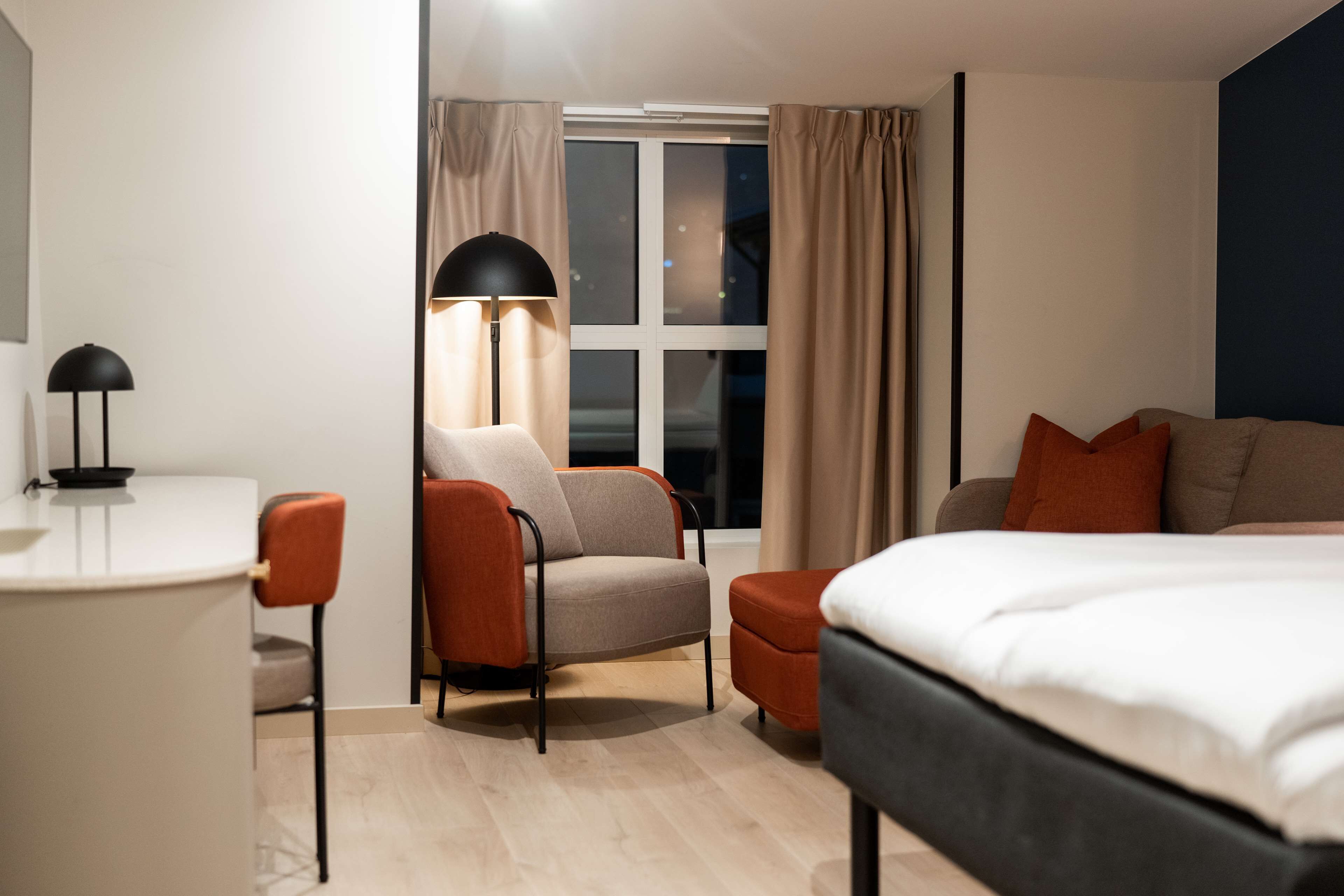 Una habitación de hotel moderna con una cama, un escritorio, una silla y una lámpara.