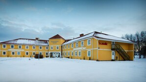 A yellow building with multiple windows and a staircase, surrounded by snow. - Scandic Leknes Lofoten (Vestvågøy)
