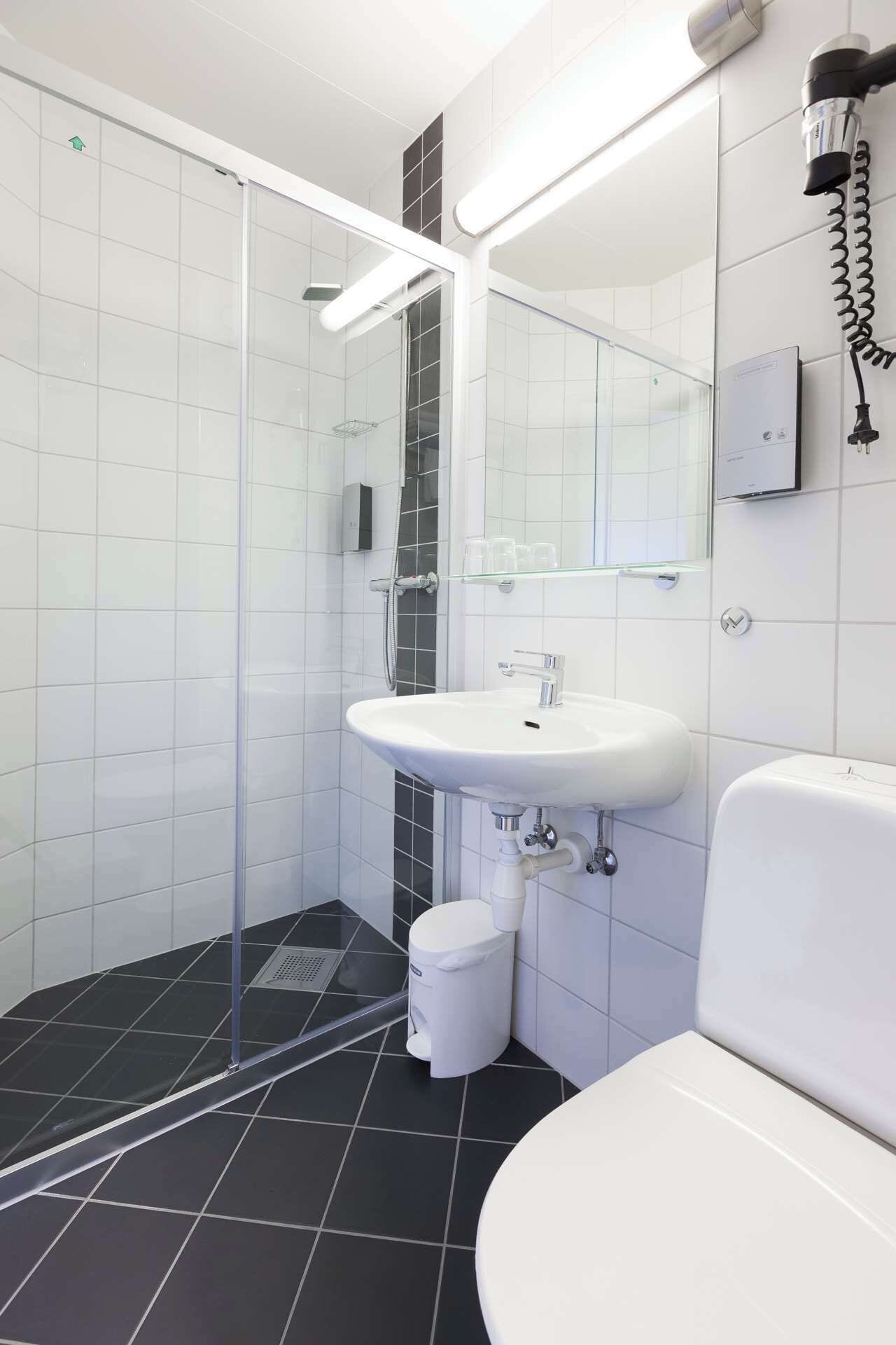 Een moderne badkamer met een glazen douchecabine, een wit wastafelmeubel en een toilet.