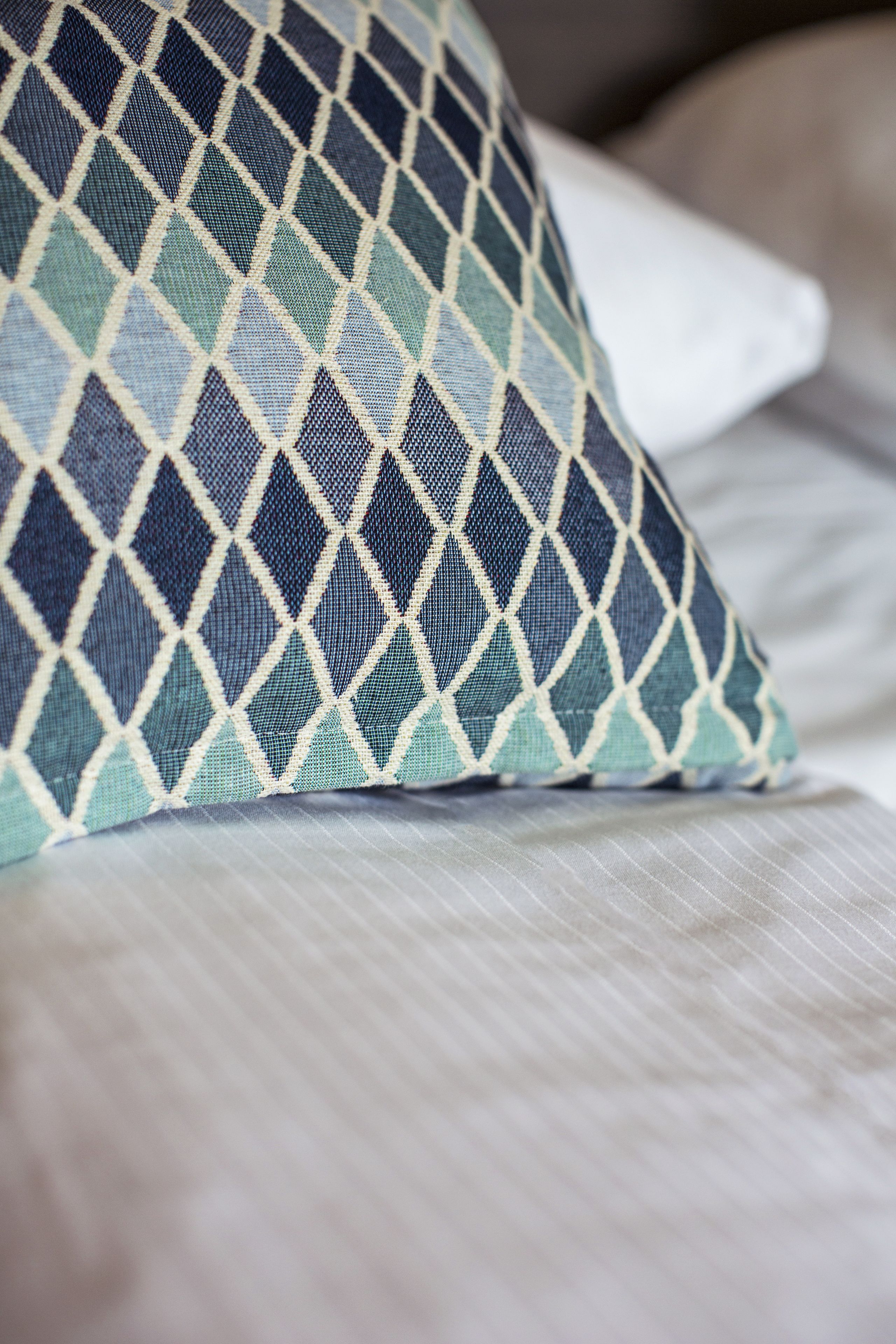 Un gros plan d’un coussin à motifs posé sur un lit.