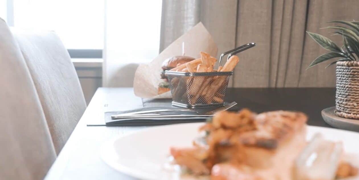 A dining table with a basket of fries, a burger, and a plate of food.