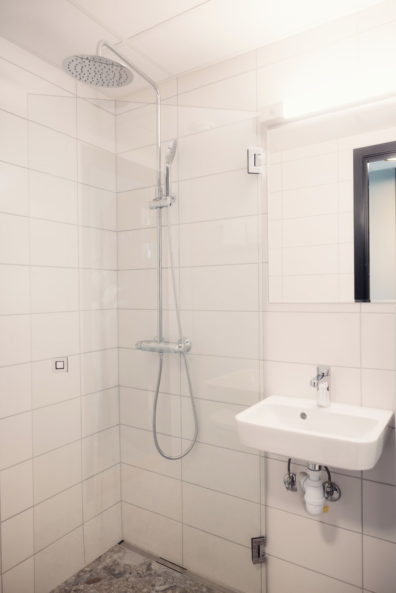 Ein modernes Badezimmer mit Dusche, Waschbecken und Spiegel.