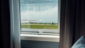 Une chambre avec une grande fenêtre donnant sur un lac et des montagnes.