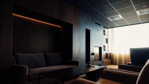 Un salon moderne avec un canapé, des fauteuils, une table basse et un téléviseur.