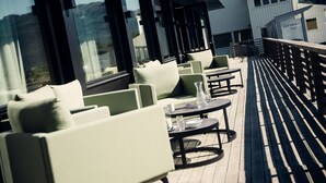 Une terrasse avec coin salon extérieur, de grandes fenêtres et une vue sur les montagnes.