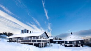 Un bâtiment recouvert de neige, doté d’un grand balcon et d’un autre bâtiment plus petit situé à côté.