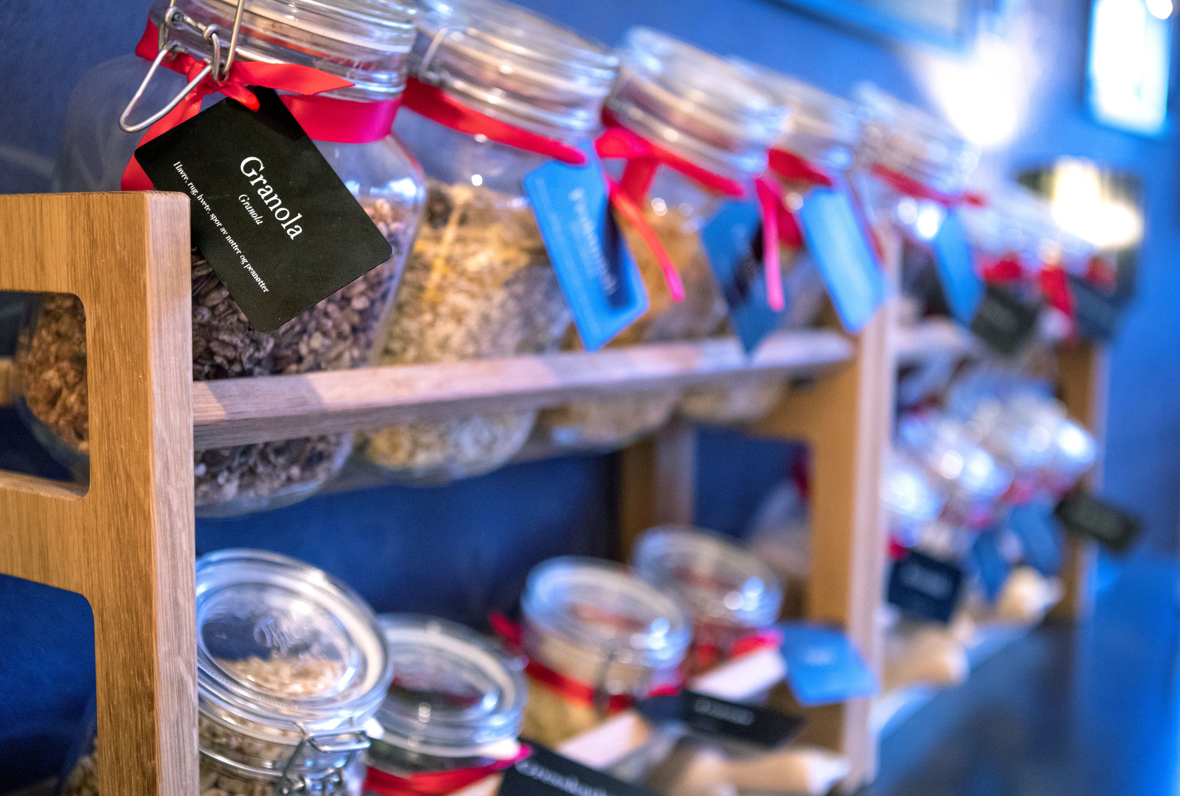 A shelf with multiple jars of granola, each with a tag.
