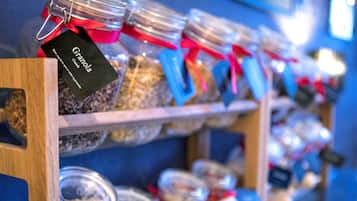 A shelf with multiple jars of granola, each with a tag.