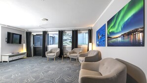 Une chambre d’hôtel moderne dotée d’une grande fenêtre, d’un téléviseur à écran plat, d’un canapé et de deux fauteuils.