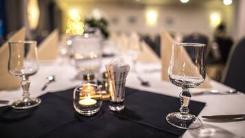 A dining table set with clear glassware, candles, and a black table runner.