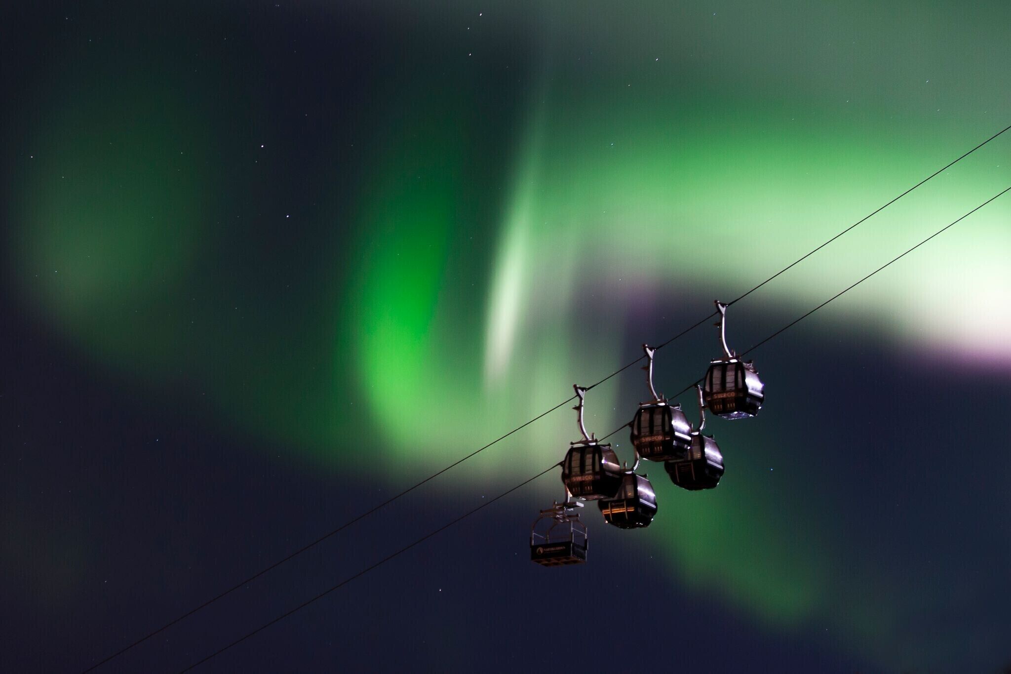 A cable car system against a night sky with the Northern Lights.