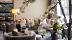 A modern living room with a sofa, armchairs, a lamp, and a vase with flowers. - Thon Hotel Andrikken (Andoy)
