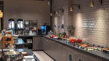 Montaje de bufé con diferentes opciones de comida, una máquina de café y una estación de té.