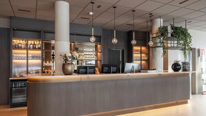 A modern reception desk with a bar area, large columns, and hanging plants. - Thon Hotel Andrikken (Andoy)
