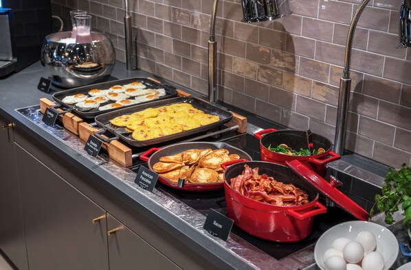 A buffet with various food options including eggs, pancakes, and bacon.