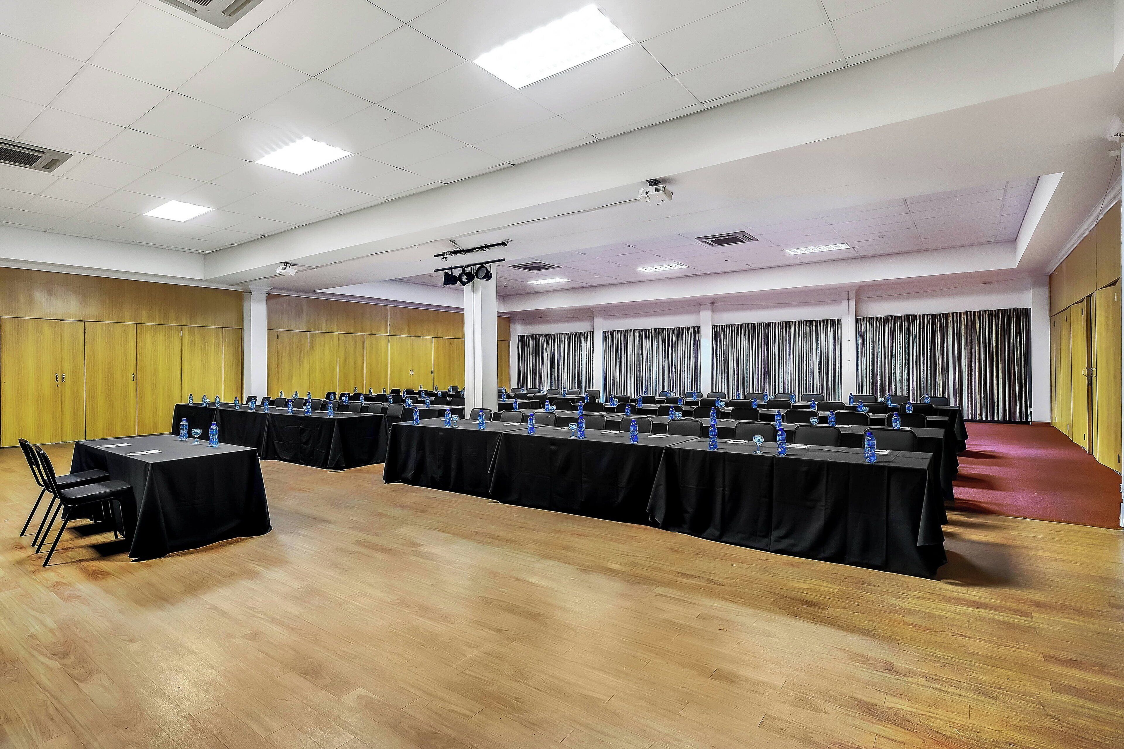 A conference room with multiple tables, chairs, and a podium.
