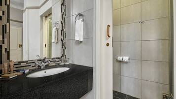 A modern bathroom with a black granite sink, a large mirror, and a shower area with tiled walls.