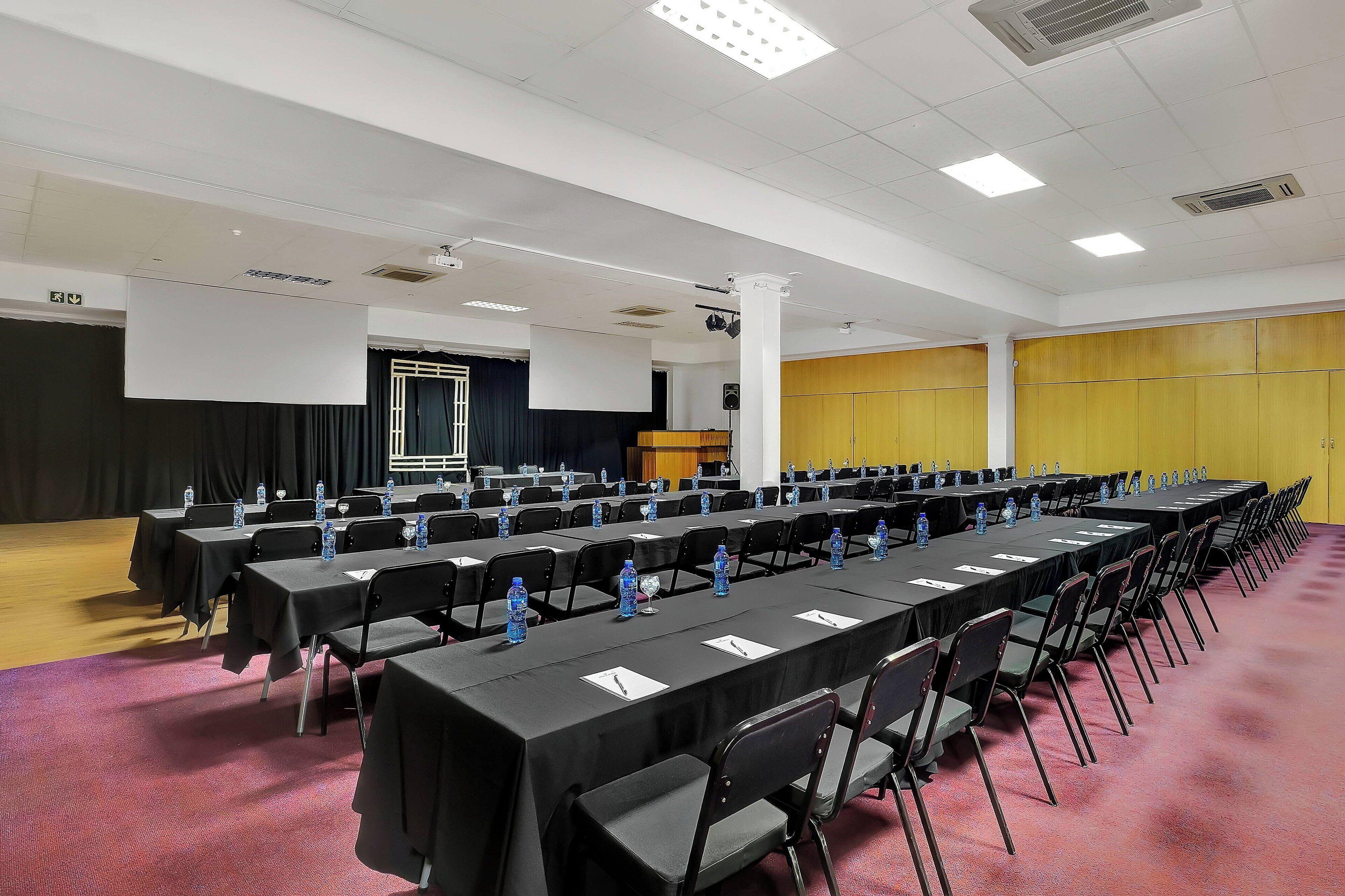 A conference room with rows of tables, chairs, and water bottles.