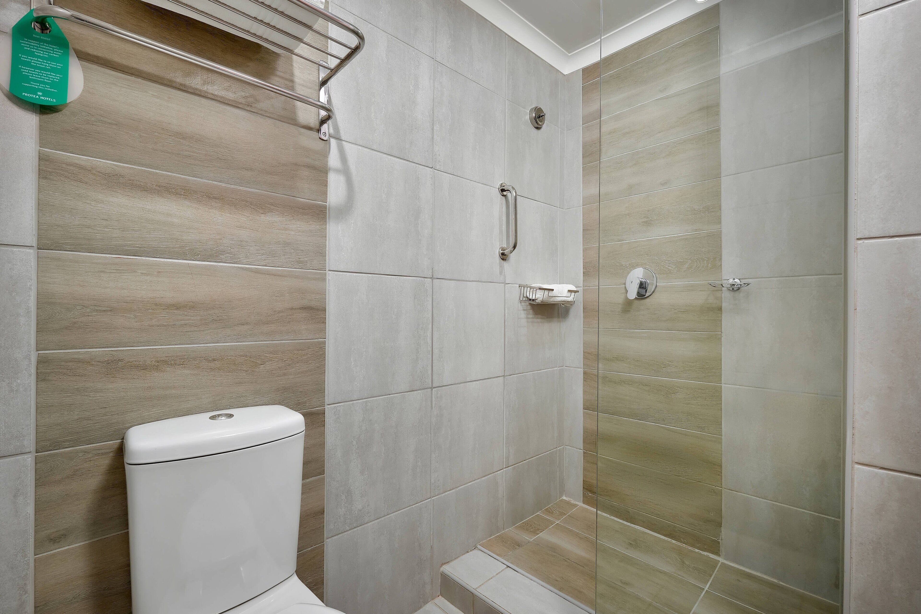 A modern bathroom with a toilet, grab bars, and a shower area.