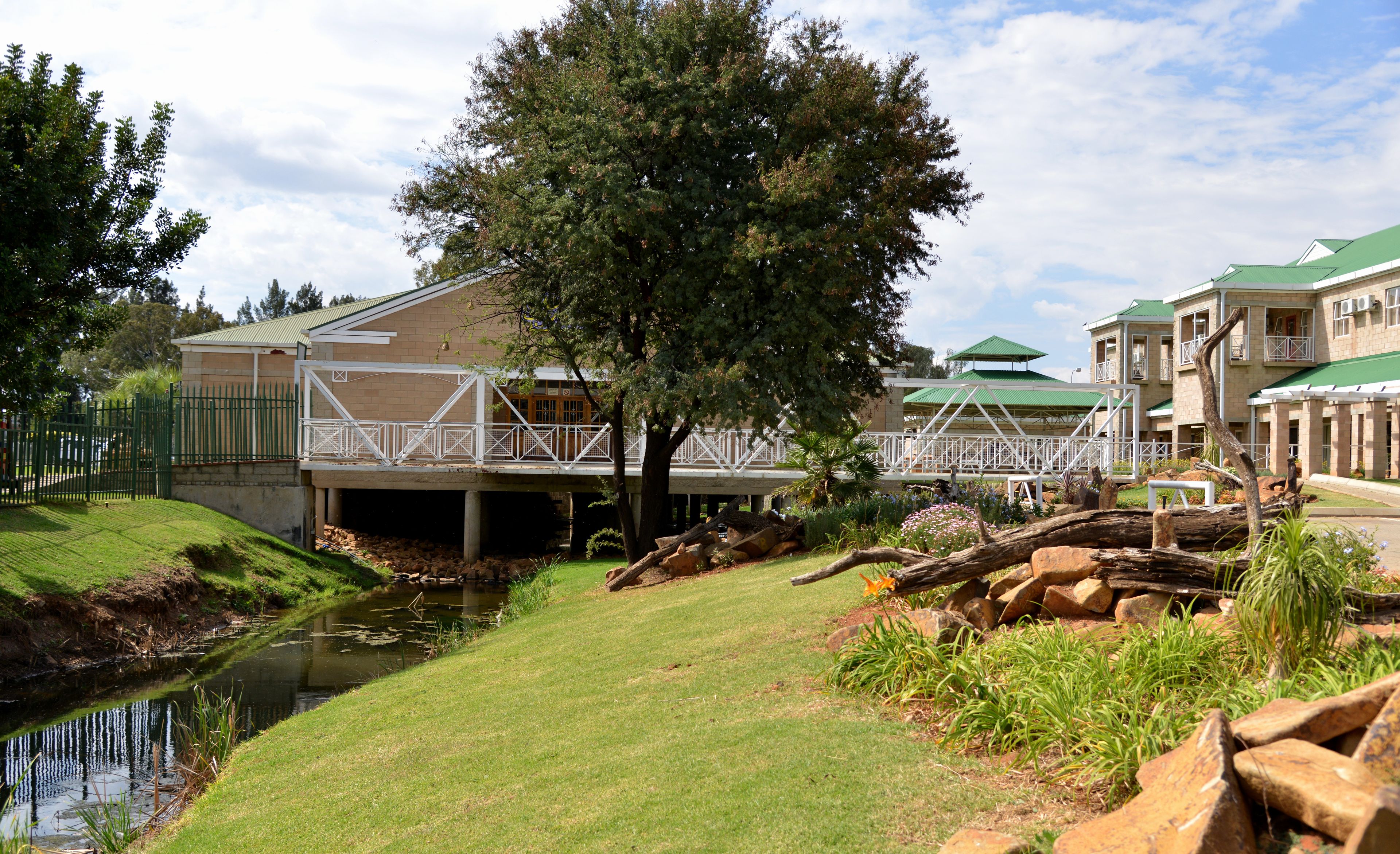 A building with a green roof, a bridge, and a pond.