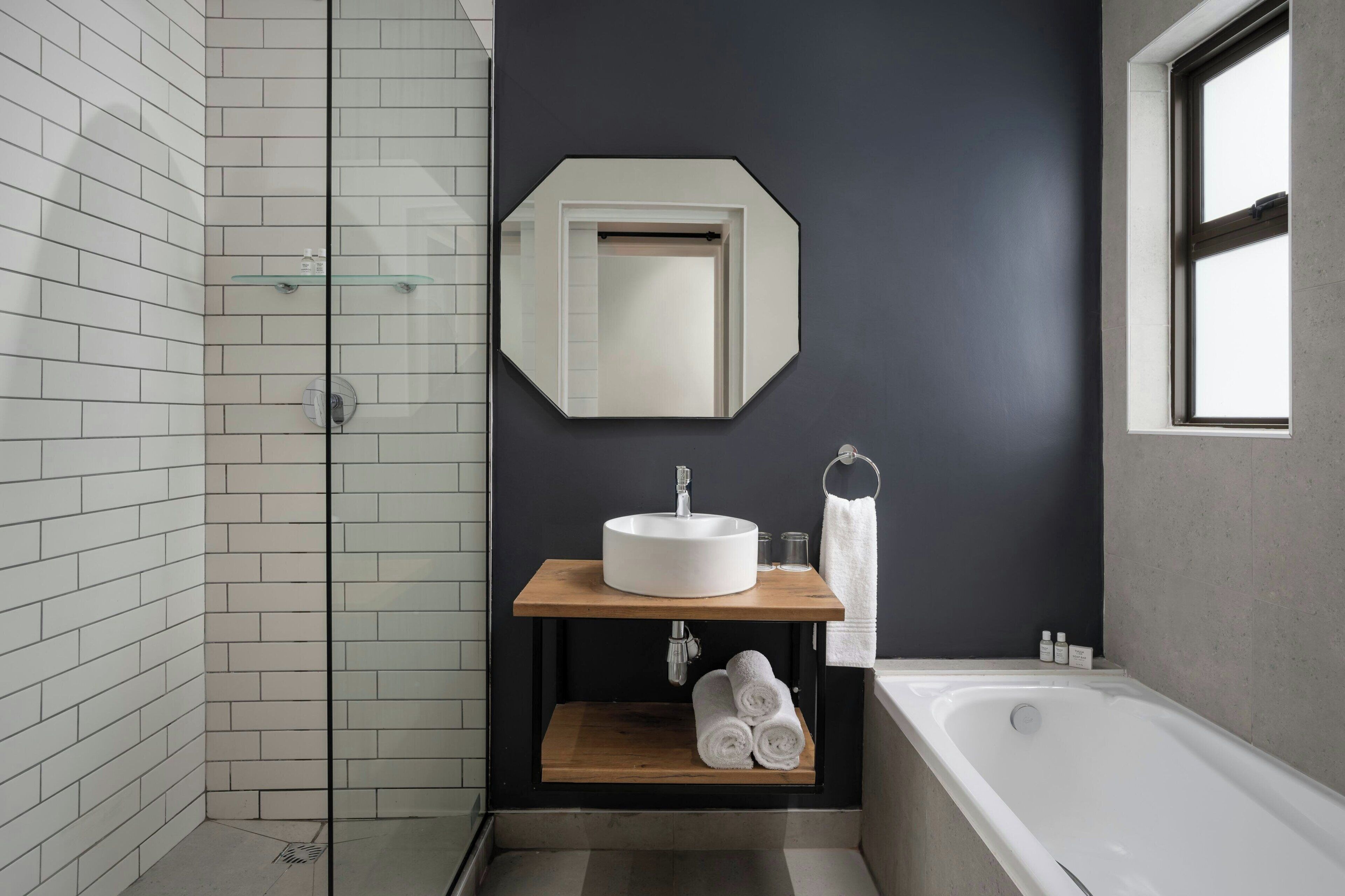 A modern bathroom with a white sink, a mirror, and a bathtub.