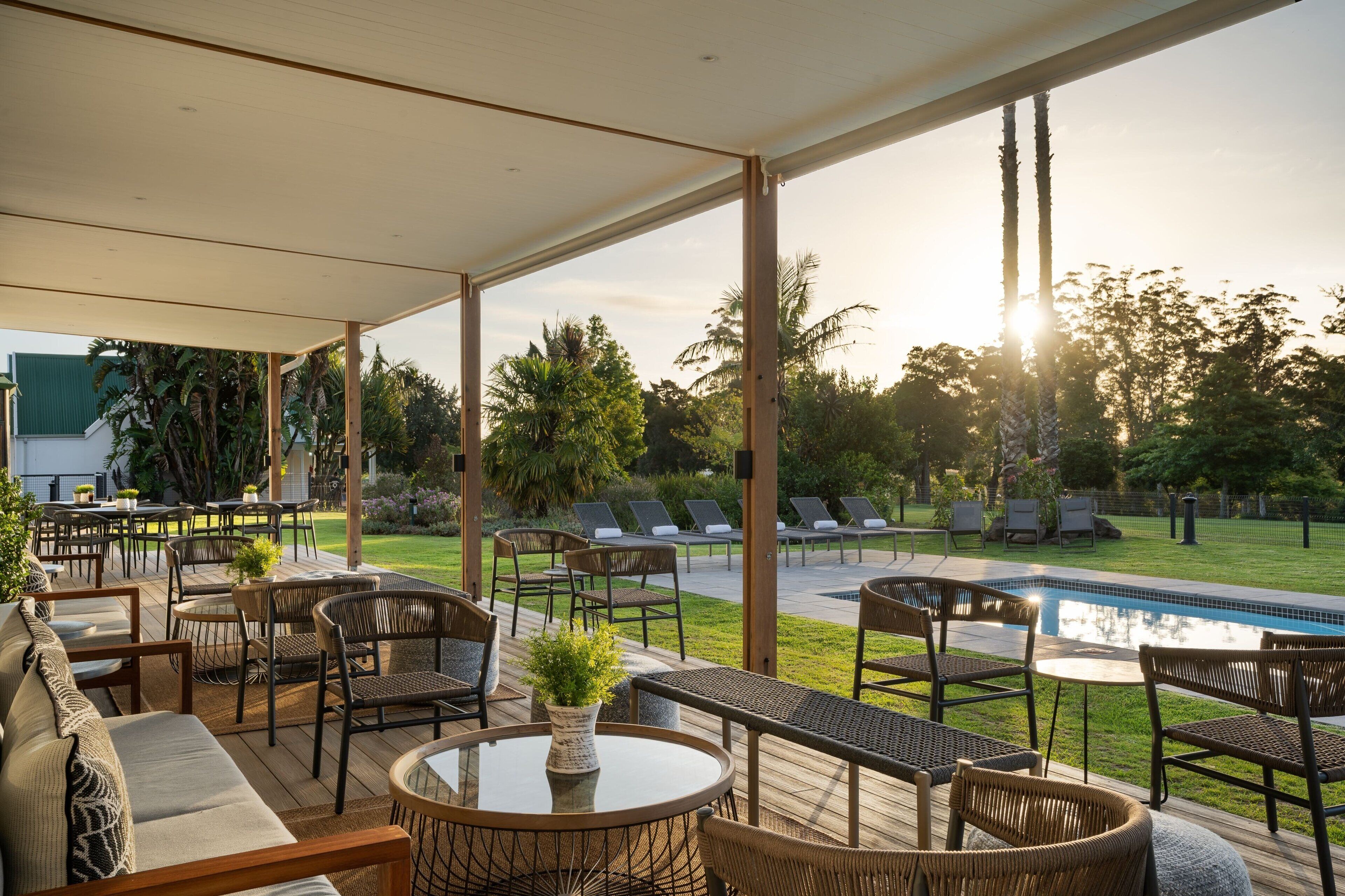 An outdoor patio area with seating, a pool, and a view of the surrounding greenery.