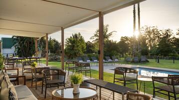 An outdoor patio area with seating, a pool, and a view of the surrounding greenery.