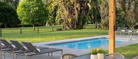 A pool area with lounge chairs, a table, and potted plants.