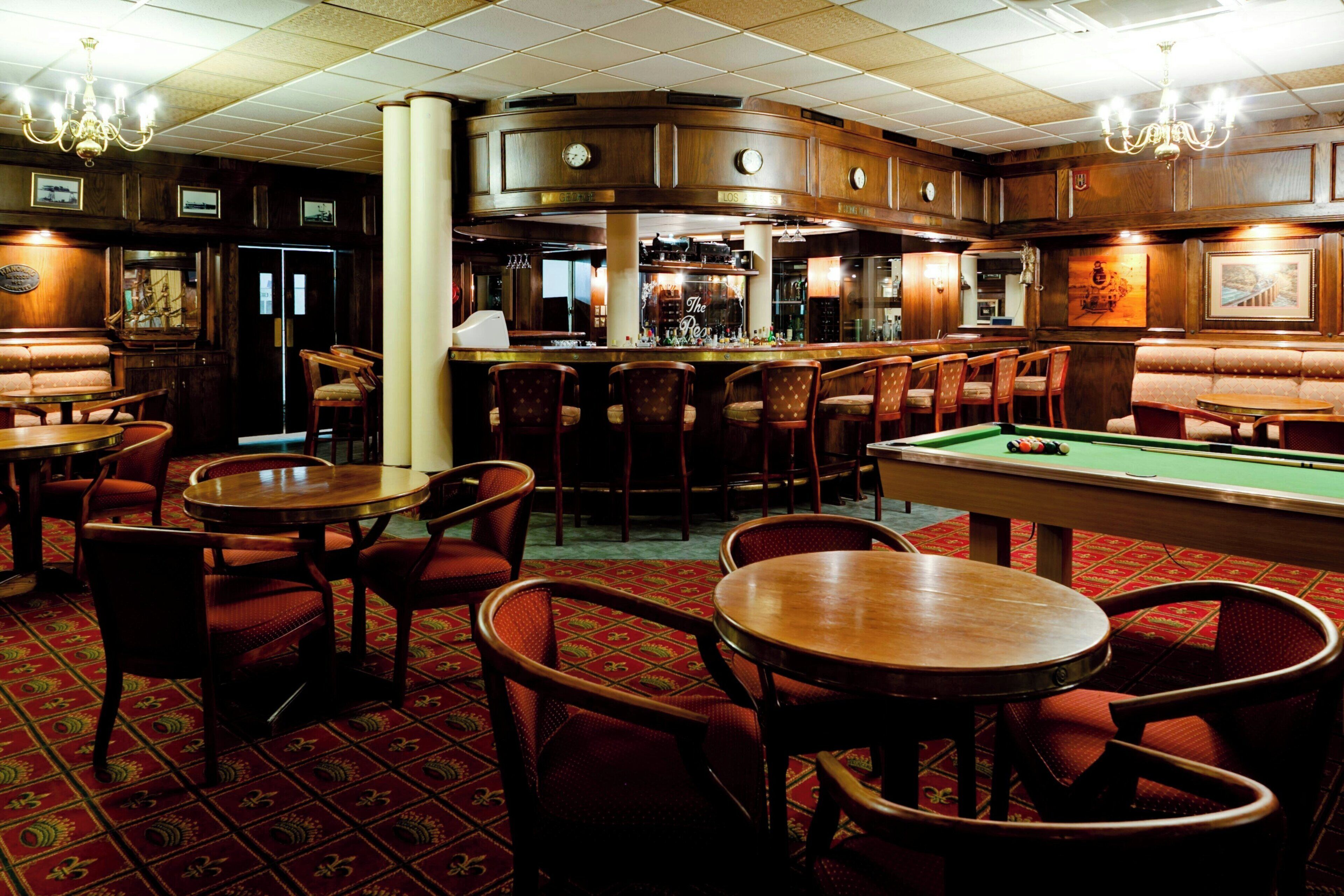 A bar area with wooden furniture, a pool table, and a billiards table.