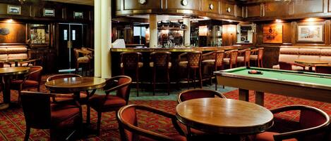 A bar area with wooden furniture, a pool table, and a billiards table.
