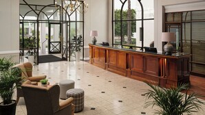 A spacious lobby with a large wooden reception desk, comfortable seating, and a chandelier. - Protea Hotel by Marriott George King George (George)