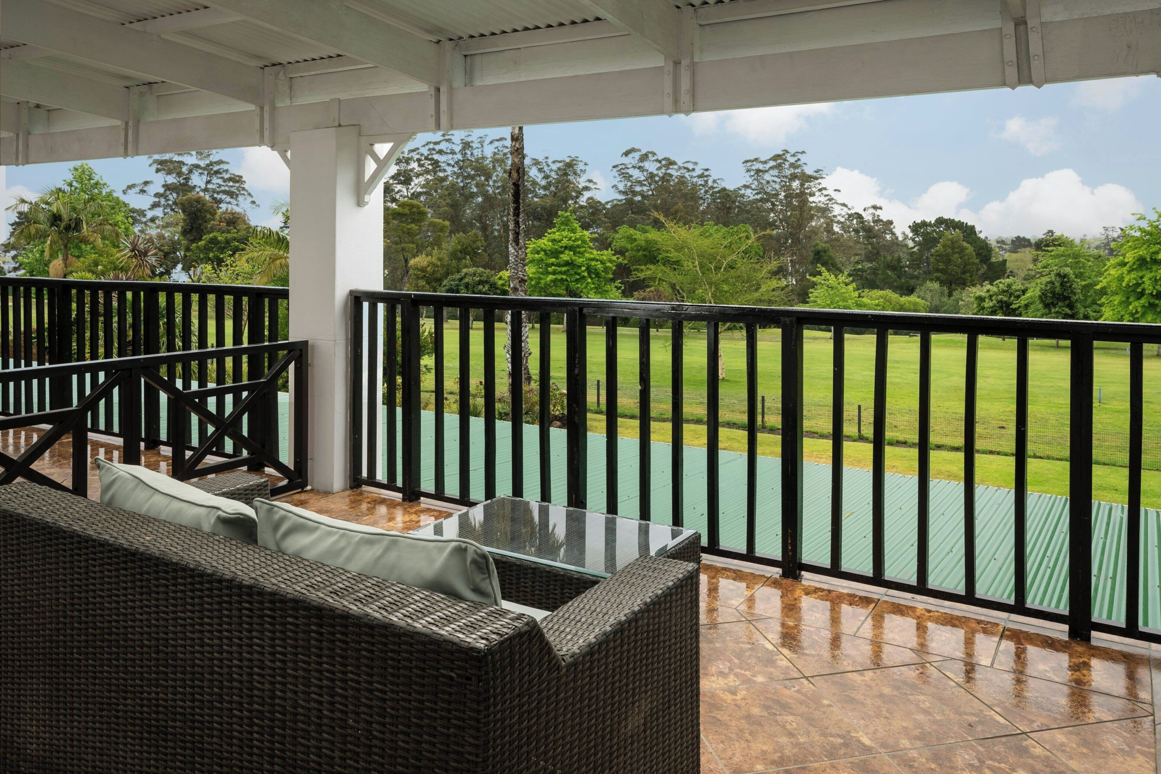 A covered outdoor seating area with a view of a green field.