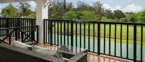 A covered outdoor seating area with a view of a green field.