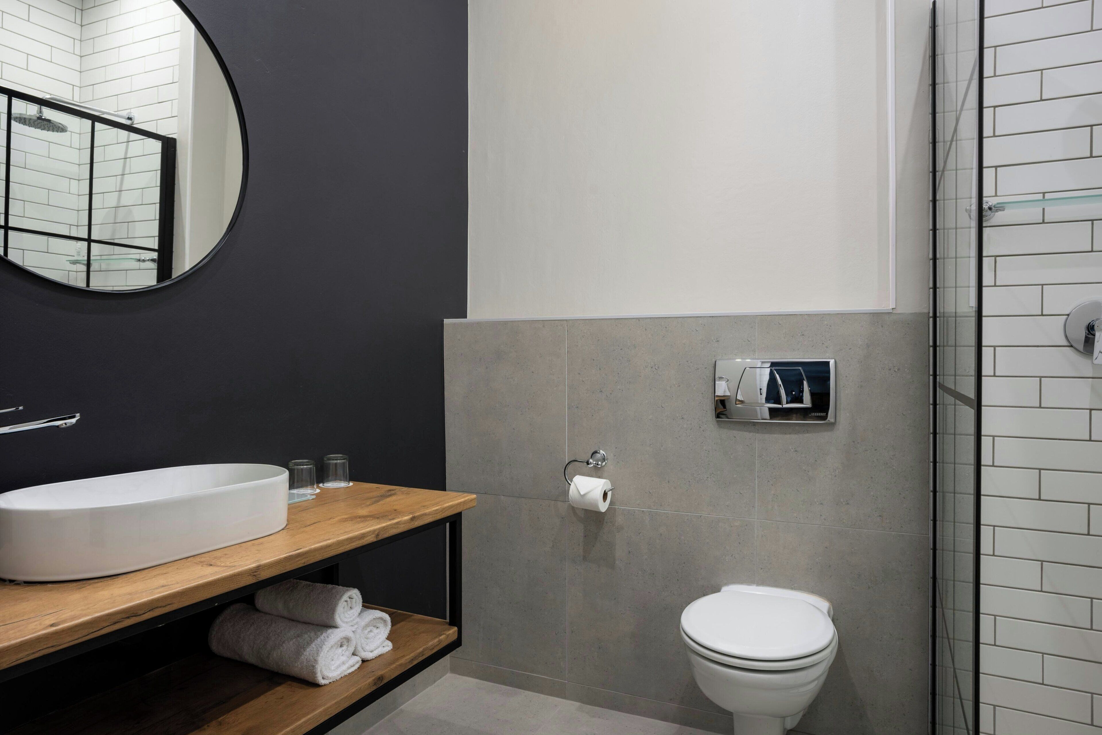 A modern bathroom with a large oval sink, a toilet, and a glass shower enclosure.