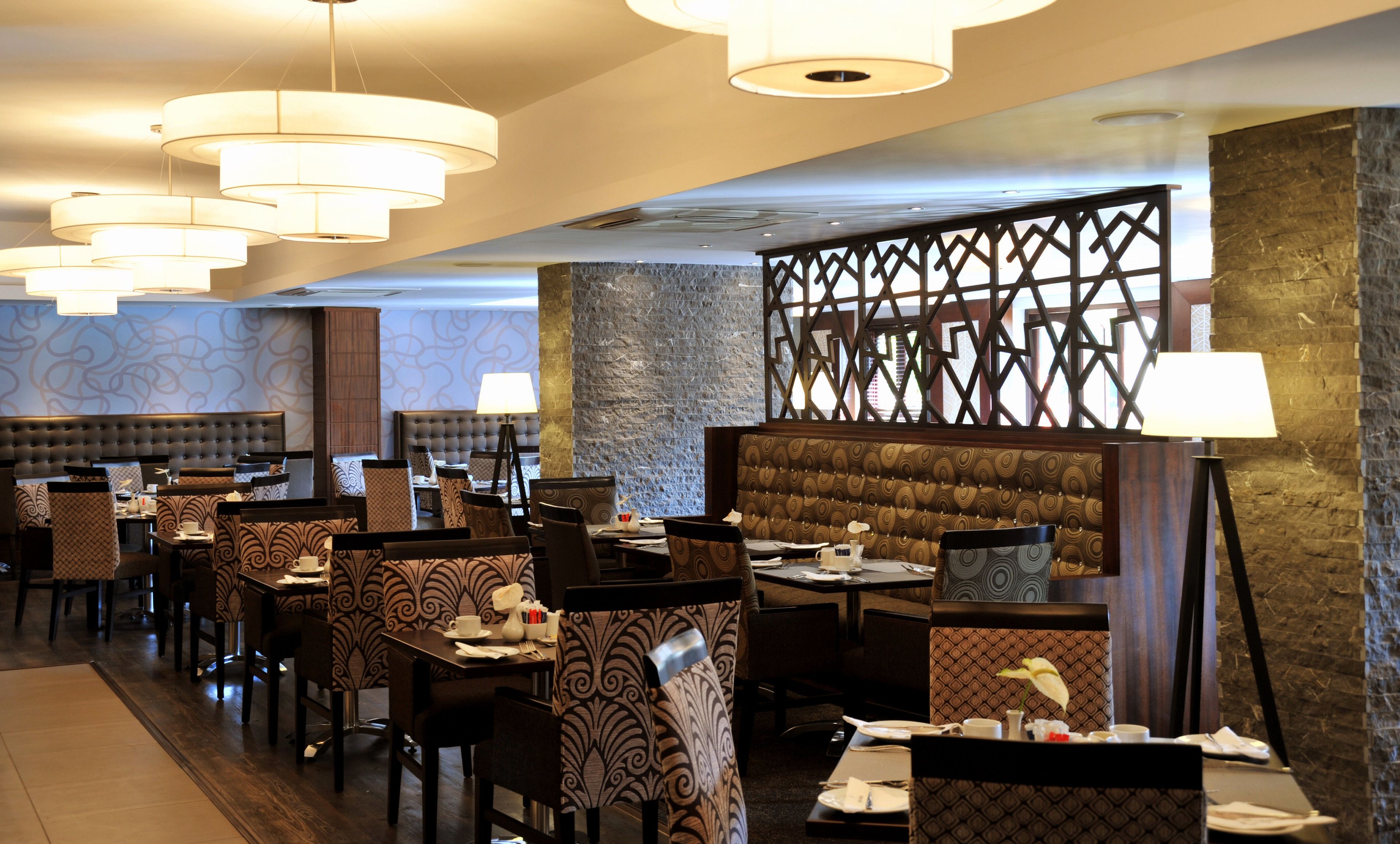 A restaurant with multiple dining booths and tables, each with a lamp and a vase of flowers.